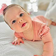Luciana is registered to the contest to win money with this photo: baby, infant, child, pink_bow, blue_eyes, crawling, bed, white_bedspread, soft_texture, natural_light, curious_expression, close_up, portrait, indoor, cute, small_hands, sleepwear, toddler, headband, skin