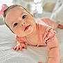baby, infant, child, pink_bow, blue_eyes, crawling, bed, white_bedspread, soft_texture, natural_light, curious_expression, close_up, portrait, indoor, cute, small_hands, sleepwear, toddler, headband, skin