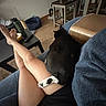 animal, black_cat, carpet, casual, cat, cat_paw, comfortable, couch, furniture, home, indoors, legs, living_room, person, pet, relaxing, remote_control, resting, table, water_bottle