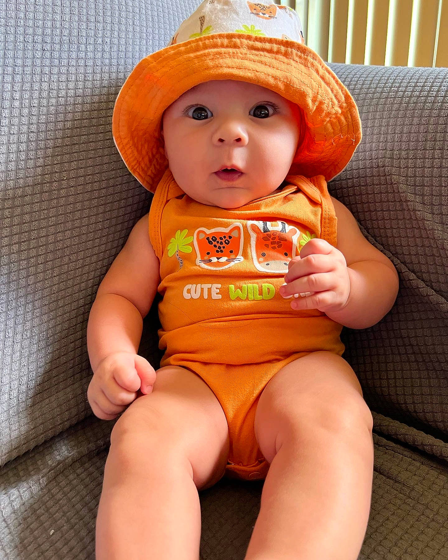Dreysten is registered to the contest to win money with this photo: abdomen, arm, baby, baby_toddler_clothing, cap, chest, face, head, headgear, headwear, human_body, knee, neck, orange, person, skin, sleeve, stomach, surprise, thigh