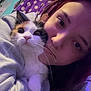 Mika is registered to the contest to win money with this photo: person, cat, calico_cat, indoor, selfie, purple_lighting, blanket, polka_dot, face, fur, whiskers, cozy, close_up, casual_clothing, pet, cute, snuggle, young_adult, expression, home
