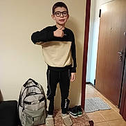 Claudio Teixeira a rejoint le concours — aidez-le/la à gagner de superbes lots ! child, boy, glasses, thumbs_up, indoor, bench, backpack, slippers, sneakers, door, tile_floor, casual_clothing, black_pants, black_beige_sweater, person, home, floor_mat, standing, young, smile