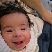 Adam is registered to the contest to win money with this photo: baby, infant, smile, laughing, face, closeup, blanket, swaddle, hair, cheek, eyes, mouth, tongue, hand, arm, indoors, cozy, portrait, happy, cute