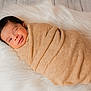 Adam is registered to the contest to win money with this photo: baby, newborn, swaddled, blanket, fur_rug, smile, portrait, indoor, cozy, fabric, texture, head, hair, sleeping, resting, soft, wrapped, beige, photography, close_up