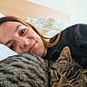 woman, cat, tabby_cat, bed, pillow, smile, face, indoor, resting, cozy, fur, headboard, blanket, pet, companion, sleepy, comfort, closeup, human, animal