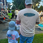 Asher is registered to the contest to win money with this photo: adult, advertisement, baseballcap, boy, cap, child, clothing, footwear, grass, hat, male, man, person, poster, shoe, shorts, sleeve, t_shirt, text, urban