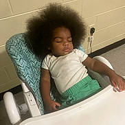 Damon joined the competition — help win amazing prizes! toddler, child, sleeping, high_chair, afro_hair, white_shirt, green_pants, indoor, wall, electrical_outlet, floor, furniture, resting, peaceful, young_child, person, baby, casual_clothing, seat, relaxing