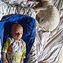 baby, sleeping, cat, white_cat, bed, blanket, pajamas, blue_cushion, indoor, resting, peaceful, cute, animal, child, nap, soft_light, home, furniture, comfort, relaxation