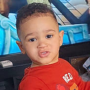 Zayn participe au concours pour gagner de l'argent avec cette photo : child, toddler, boy, portrait, face, curly_hair, big_eyes, red_shirt, lion_graphic, expression, living_room, television, tv_show, background_characters, ear, smile, close_up, furniture, remote_control, floor