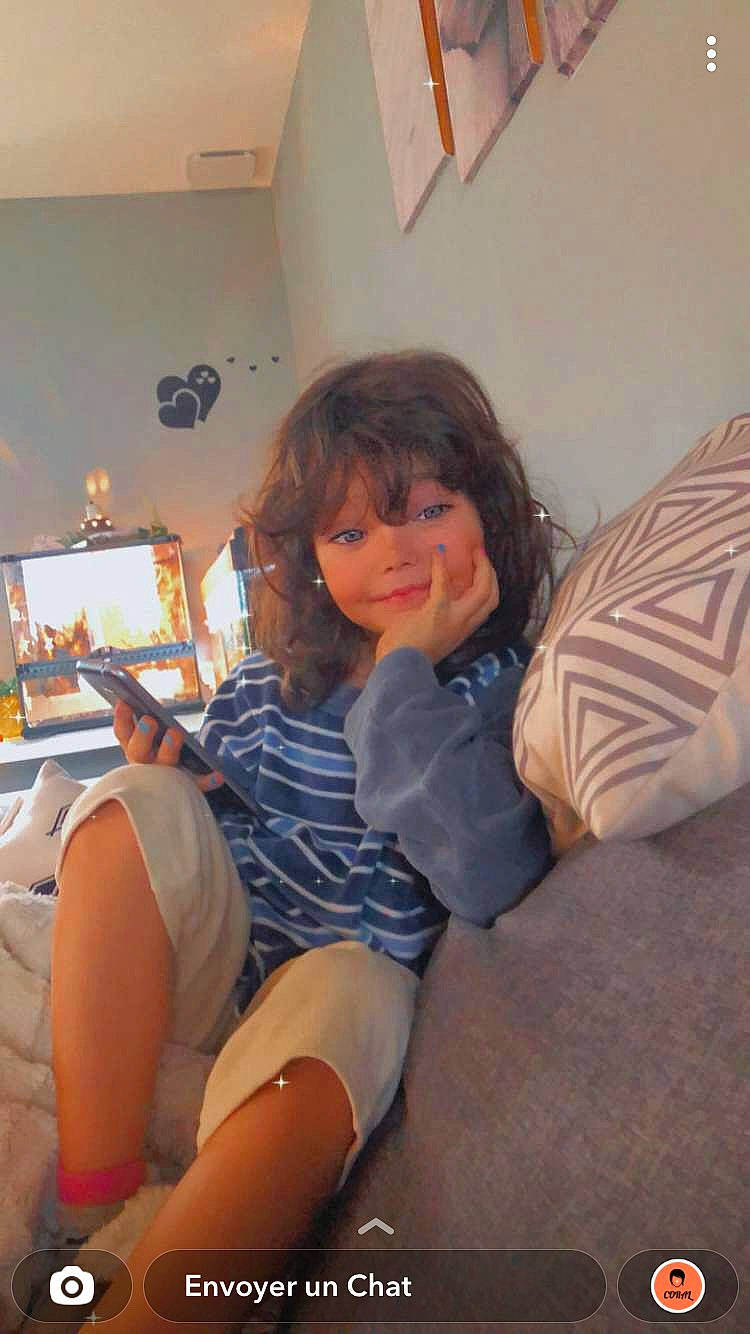 Louna participe au concours pour gagner de l'argent avec cette photo : abdomen, brown_hair, child, comfort, flooring, fun, happy, human_leg, knee, lap, leg, leisure, living_room, person, picture_frame, room, shorts, sitting, thigh, trunk