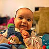 baby, child, smiling, cute, denim, monkey_patch, toy, food, messy, face, portrait, indoor, playful, happy, young_child, clothing, colorful, hands, expression, infant