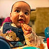 Amelia is registered to the contest to win money with this photo: baby, child, food, bib, monkey, indoor, happy, cute, munching, curious_eyes, high_chair, toy, colorful, clothing, face, hand, smile, messy, infant, portrait