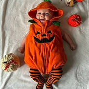 James joined the competition — help win amazing prizes! baby, pumpkin_costume, hooded_outfit, striped_leggings, blanket, knitted_pumpkin, orange, white, flowers, smiling, cute, infant, lying_down, fall_theme, decor, cozy, child, portrait, festive, holiday