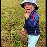 bracelet, bucket_hat, child, cow, cows, daytime, farmhouse, field, grass, jacket, outdoors, pants, pasture, playful, portrait, rural, screenshot, smiling, toddler, tongue_out
