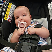 Gracie is registered to the contest to win money with this photo: baby, infant, child, car_seat, pacifier, sitting, portrait, face, eyes, smiling, clothing, harness, seat_belt, shopping_store, grocery_shelves, indoor, safe, vehicle_seat, photography, adorable