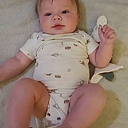 Ethan is registered to the contest to win money with this photo: baby, infant, child, onesie, blanket, soft_toy, hand, cute, lying_down, indoor, person, skin, face, expression, young_child, cozy, animal_print, comfort, holding, gentle