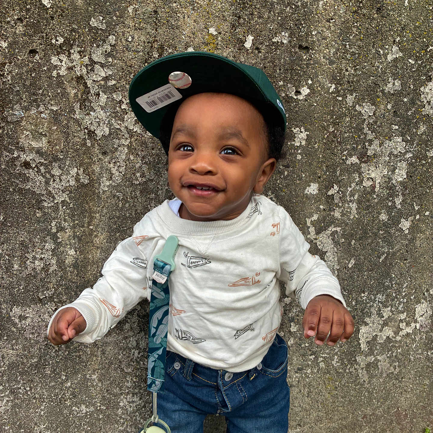 Dwane Jr. joined the competition — help win amazing prizes! toddler, child, smiling, cap, baseball_cap, barcode, white_sweatshirt, denim_jeans, pacifier, clip, standing, wall, textured_wall, outdoor, happy, person, clothing, casual, cute, portrait