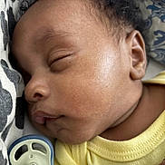 Dwane Jr. is registered to the contest to win money with this photo: baby, sleeping, close_up, pacifier, yellow_clothing, curly_hair, pillow, face, peaceful, infant, skin, ear, mouth, hand, resting, cozy, newborn, portrait, child, indoors