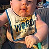 baby, infant, child, sitting, portrait, face, smiling, happy, indoor, bib, food, messy_face, orange_food, clothing, hands, arms, chair, household_items, closeup, photography
