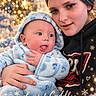 baby, child, infant, portrait, cuddling, smiling, christmas, christmas_tree, holiday, winter, snowflakes, hearts, cozy, blanket, hooded_outfit, blue_clothing, indoor, fairy_lights, family, text_overlay