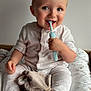 baby, bed, child, comfort, cushion, cute, face, hand, happy, indoor, infant, light, neutral_background, pajamas, sitting, smiling, soft_toys, stuffed_animal, teething_toy, toddler