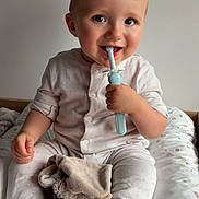 Gabin a rejoint le concours — aidez-le/la à gagner de superbes lots ! baby, bed, child, comfort, cushion, cute, face, hand, happy, indoor, infant, light, neutral_background, pajamas, sitting, smiling, soft_toys, stuffed_animal, teething_toy, toddler