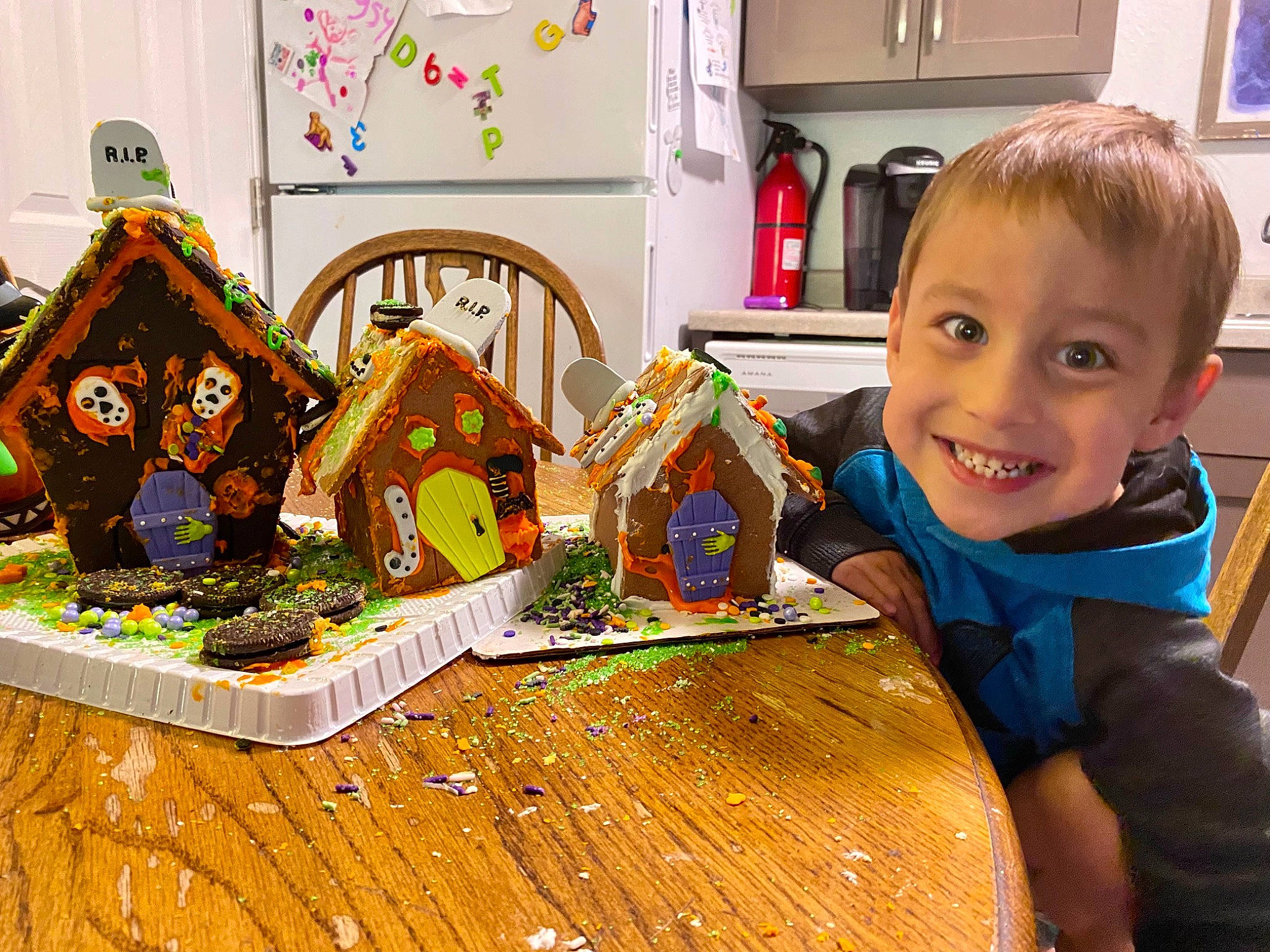 Kyler is registered to the contest to win money with this photo: baking, child, desk, dessert, event, food, holiday, home_accessories, joy, person, picture_frame, play, refrigerator, room, sharing, smile, t_shirt, table, tableware, television