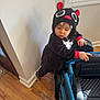 Declan joined the competition — help win amazing prizes! toddler, child, onesie, costume, monster, toy_car, indoor, wood_floor, window, curious, black_clothing, red_ears, white_teeth, baby, person, home, play, floor, hands, face