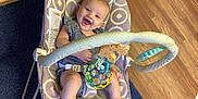 Khaleesi is registered to the contest to win money with this photo: baby, smiling, baby_rocker, toy, indoor, flooring, carpet, happy, child, infant, playtime, seat, patterned, colorful, wood_floor, cute, person, small, legs, clothing