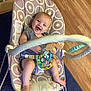 baby, smiling, baby_rocker, toy, indoor, flooring, carpet, happy, child, infant, playtime, seat, patterned, colorful, wood_floor, cute, person, small, legs, clothing