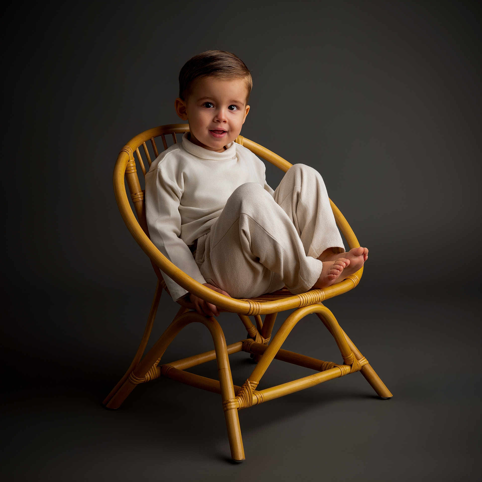 Rafaël participe au concours pour gagner de l'argent avec cette photo : toddler, child, smile, chair, bamboo_chair, beige_clothing, studio_lighting, portrait, cute, sitting, indoor, young_child, fashion, comfortable, minimalist, happy, feet, pose, neutral_background, cozy