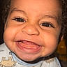 baby, toddler, smile, happy, face, curly_hair, bib, dinosaur_pattern, child, portrait, cute, teeth, skin, eyes, indoors, closeup, person, infant, joy, expression