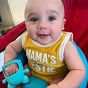 Hudson is registered to the contest to win money with this photo: baby, infant, child, smile, face, eyes, toy, blue_toy, yellow_clothing, sitting, baby_seat, red_background, arm, hand, cute, portrait, indoor, closeup, happy, skin