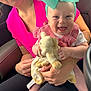 baby, woman, car, child, smile, bow, headband, toy, plush, happy, seat, clothing, pink_shirt, black_pants, hand, person, window, daylight, interior, candid
