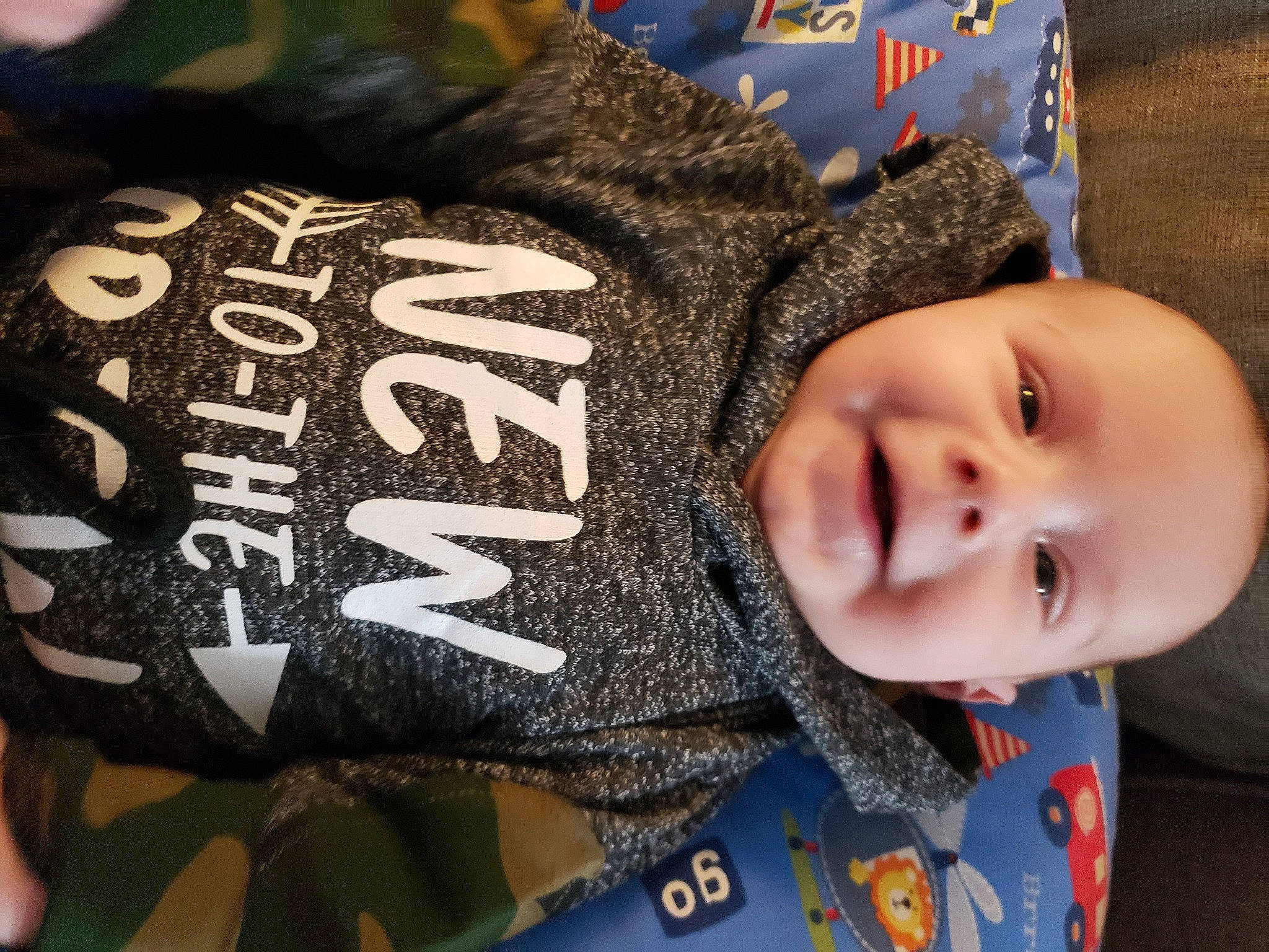 Jase is registered to the contest to win money with this photo: baby, baby_toddler_clothing, cheek, child, font, fun, happy, pattern, person, personal_protective_equipment, sleeve, smile, textile, toddler, tree, winter, wood