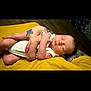 baby, newborn, sleeping, arms, tattoo, nail_polish, yellow, clothing, person, skin, hand, rest, peaceful, infant, holding, closeup, indoor, human, cute, portrait
