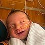 baby, infant, smiling, blanket, hospital, feeding_tube, medical_equipment, sleeping, wrapped, face, newborn, person, healthcare, cute, child, care, indoors, closeup, skin, peaceful