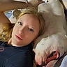 Klein is registered to the contest to win money with this photo: animal, bed, black_shirt, casual, comfort, companion, dog, face, friendship, human, indoor, light, lying_down, pet, portrait, relaxed, resting, smiling_dog, white_dog, woman