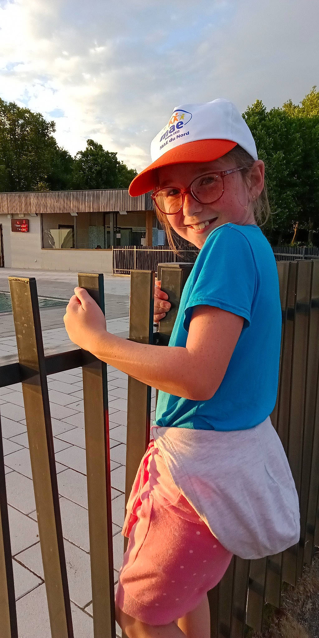 Lily-rose a rejoint le concours — aidez-le/la à gagner de superbes lots ! baseball_cap, cap, elbow, electric_blue, eyewear, fence, fun, glasses, headwear, human_body, joy, leisure, person, pink, recreation, sky, summer, t_shirt, thigh, travel