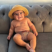 Guzey joined the competition — help win amazing prizes! baby, child, hat, straw_hat, striped_shorts, couch, sofa, gray_furniture, smile, cute, chubby, indoors, relaxed, portrait, person, skin, bare_chest, footwear_absent, seated, happy