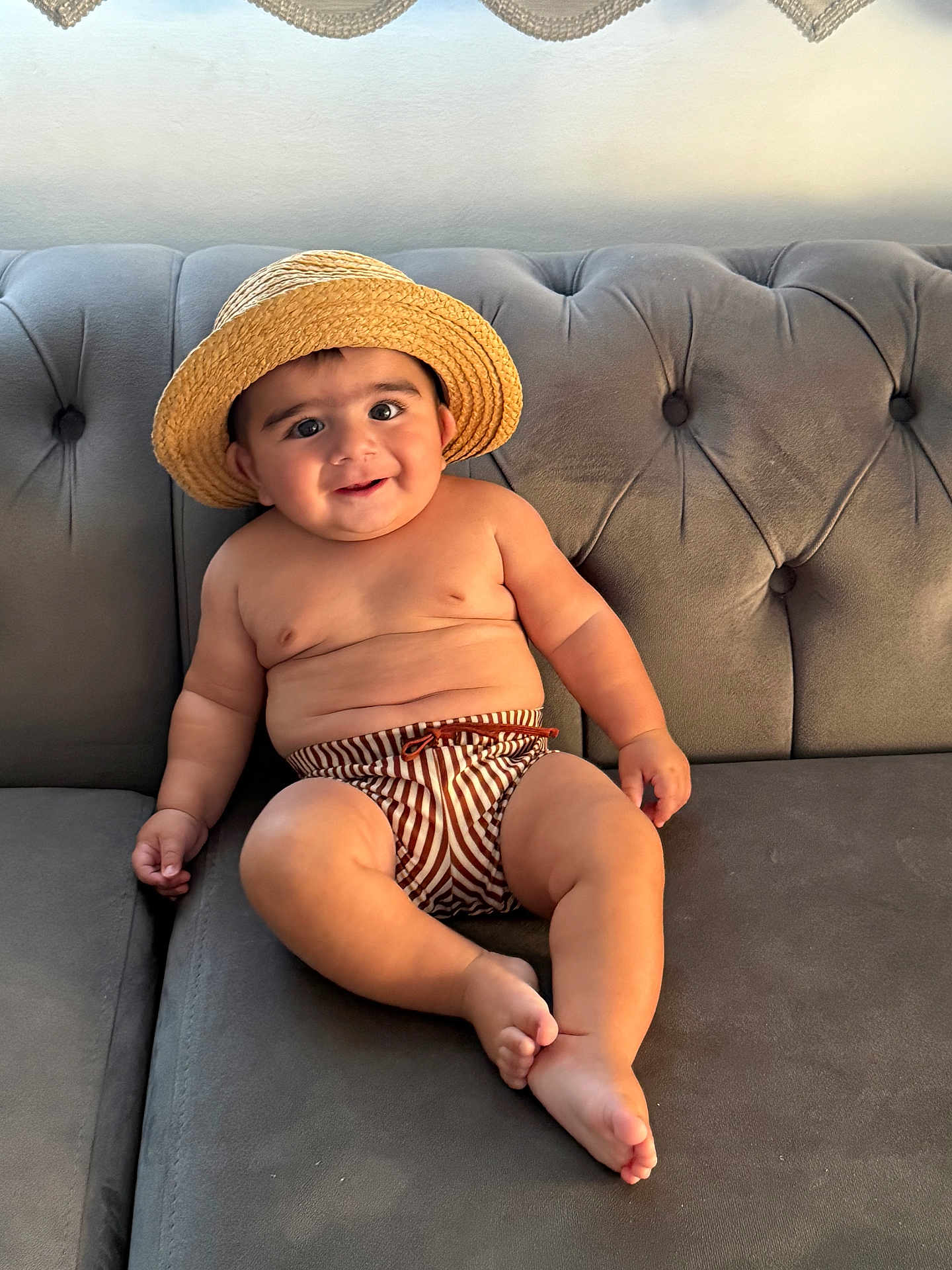 Guzey joined the competition — help win amazing prizes! baby, child, hat, straw_hat, striped_shorts, couch, sofa, gray_furniture, smile, cute, chubby, indoors, relaxed, portrait, person, skin, bare_chest, footwear_absent, seated, happy