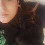 Lucifer is registered to the contest to win money with this photo: person, cat, black_cat, lying_down, indoor, close_up, face, animal, pet, eyeliner, hair, pillow, comfort, relaxation, casual, expression, fur, eyes, shirt, earring
