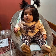 Ariana joined the competition — help win amazing prizes! baby, child, infant, pigtails, leopard_print, socks, baby_rocker, indoor, curious, clothing, table, countertop, chair, face, person, hair, cute, seated, expression, furniture