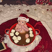 Cooper joined the competition — help win amazing prizes! baby, santa_hat, marshmallows, red_pot, christmas, holiday_decor, cotton_fluff, wooden_floor, gift_boxes, festive, infant, cute, holiday_theme, holiday_lighting, red_blanket, merry_christmas, face, person, indoors, celebration
