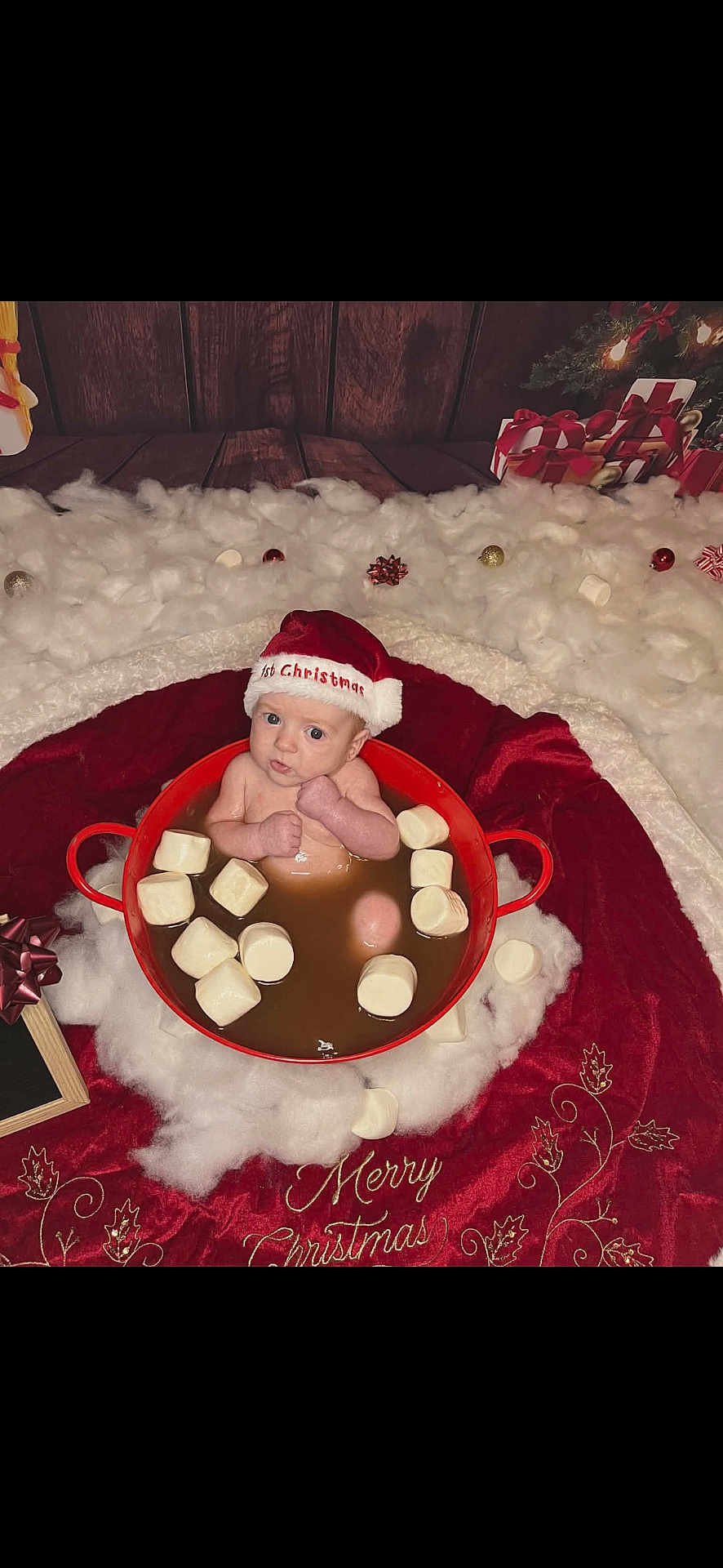 Cooper joined the competition — help win amazing prizes! baby, santa_hat, marshmallows, red_pot, christmas, holiday_decor, cotton_fluff, wooden_floor, gift_boxes, festive, infant, cute, holiday_theme, holiday_lighting, red_blanket, merry_christmas, face, person, indoors, celebration
