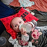 baby, bottle, blanket, bed, pillow, clothing, face, person, indoor, toy, sleepwear, child, laying_down, feeding, cute, soft, comfort, red, patterned, cozy