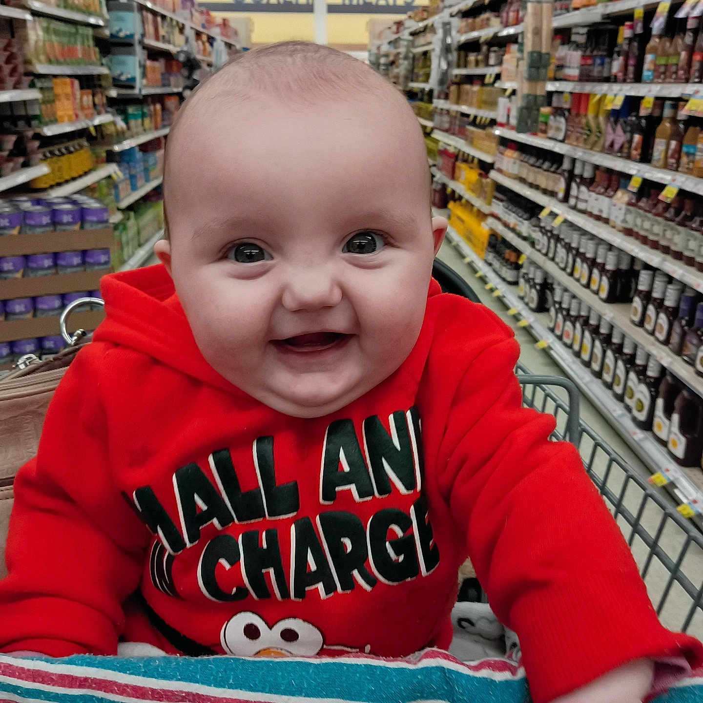 Kae-Lynn joined the competition — help win amazing prizes! baby, child, smiling, shopping_cart, red_hoodie, grocery_store, aisle, products, face, cute, happy, infant, clothing, portrait, person, retail, store_shelves, toddler, indoor, shopping