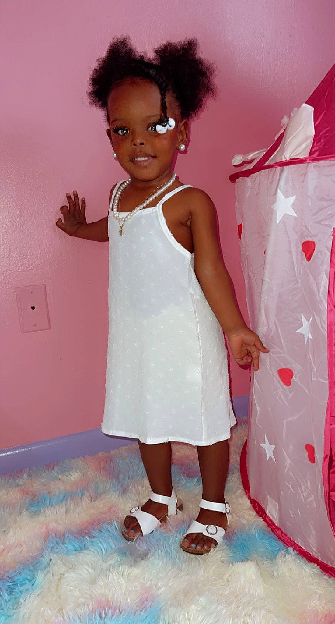 Riley is registered to the contest to win money with this photo: baby_toddler_clothing, child, day_dress, fashion_design, fun, gesture, happy, houseplant, human_leg, joint, joy, knee, magenta, one_piece_garment, pattern, person, pink, room, skin, sleeve