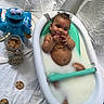 baby, bathtub, milk, cookie, cookie_monster, plush_toy, jar, chocolate_chip_cookie, crumbs, milky_water, child, smiling, happy, sitting, indoor, fabric_background, toy, milk_bath, five_months_sign, cute