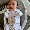 Zakkai is registered to the contest to win money with this photo: baby, infant, smiling, happy, onesie, moon_pattern, star_pattern, white_clothing, baby_seat, perforated_seat, chair, outdoor, young_child, cute, portrait, sitting, joyful, person, infant_clothing, relaxing